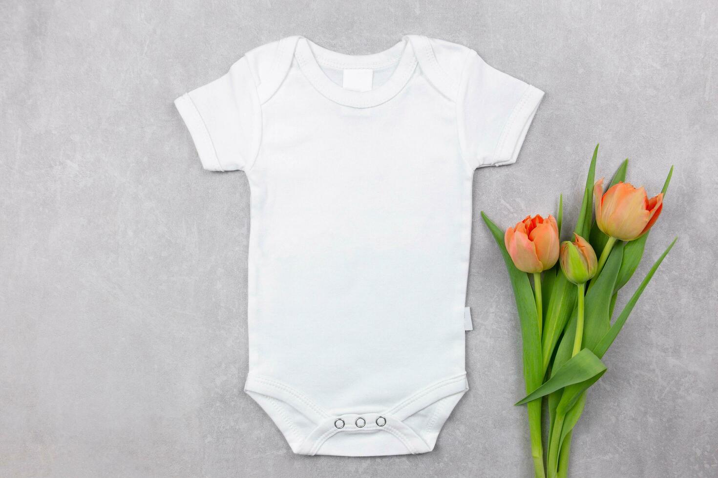 Weiß Baby Mädchen oder Junge Bodysuit Attrappe, Lehrmodell, Simulation eben legen mit Orange Tulpen Blumen Dekoration auf das grau Beton Hintergrund. Design Strampler Vorlage, drucken Präsentation spotten hoch. oben Sicht. foto