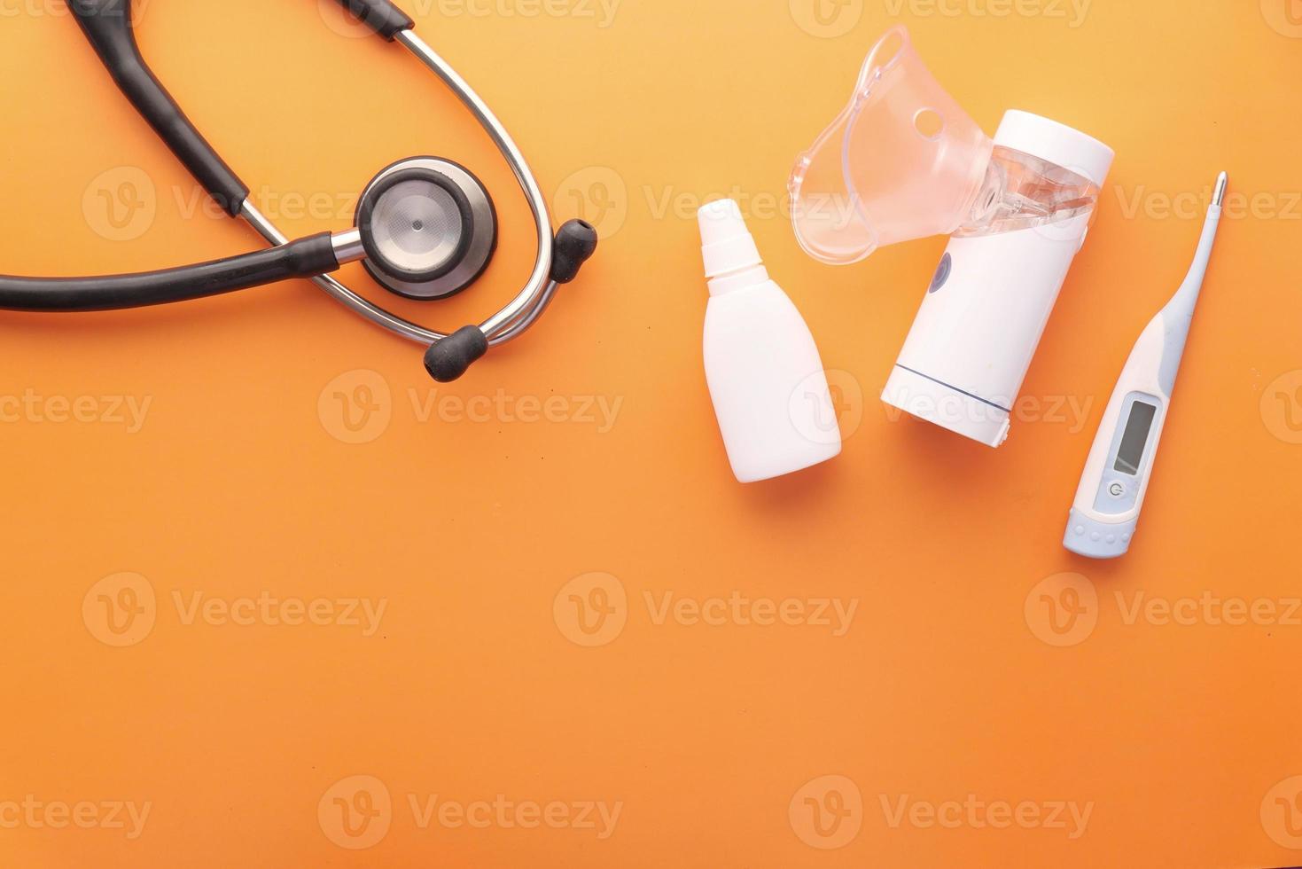 Vernebler, Thermometer und Stethoskop auf orangem Hintergrund foto