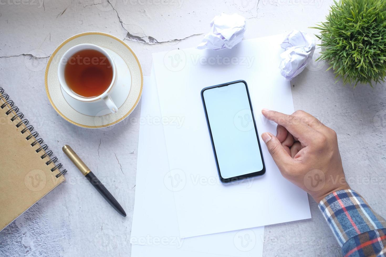 Draufsicht der Mannhand unter Verwendung des Smartphones am Schreibtisch foto