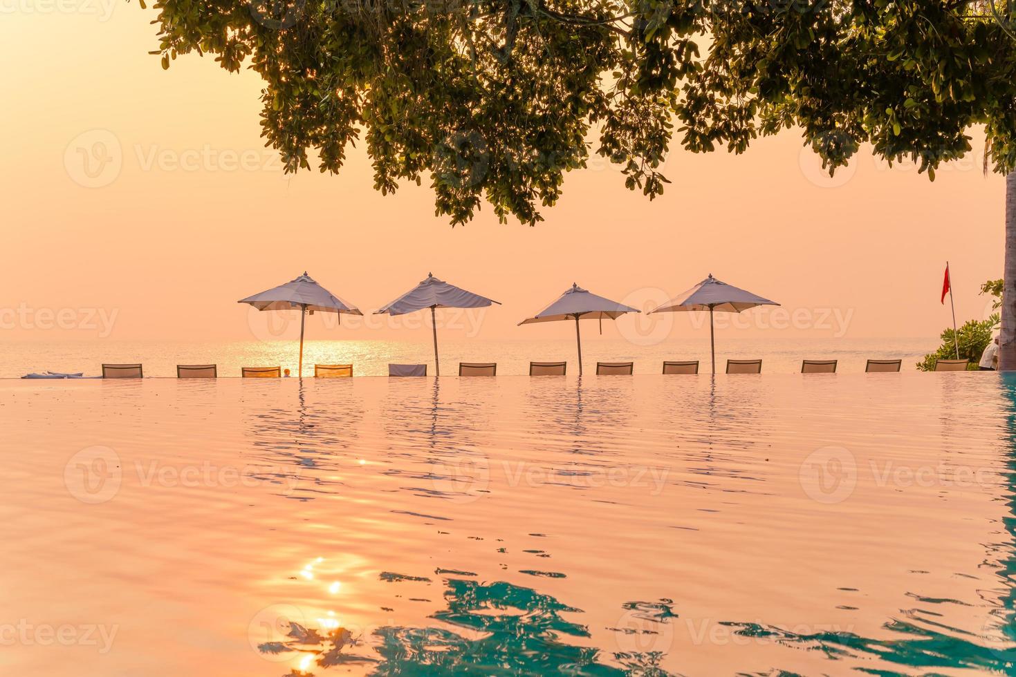 Sonnenschirm und Stuhl rund um den Pool mit Meerblick foto