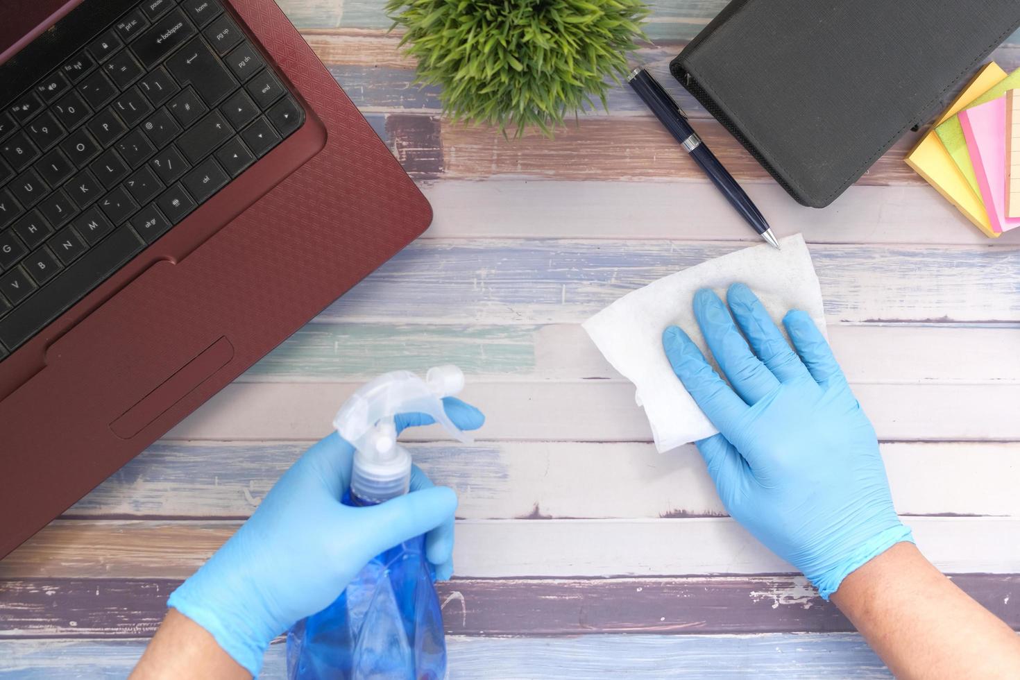 Hand in blauen Gummihandschuhen mit Sprühflaschen-Reinigungstisch foto