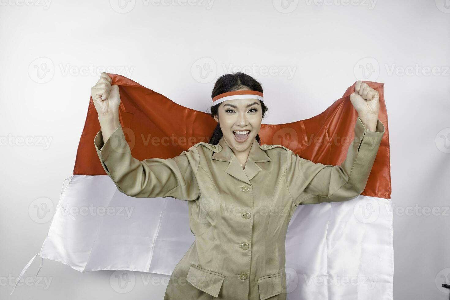 lächelnd Regierung Arbeiter Frau halten Indonesiens Flagge isoliert durch Weiß Hintergrund. pns tragen khaki Uniform. Indonesiens Unabhängigkeit Tag Konzept. foto