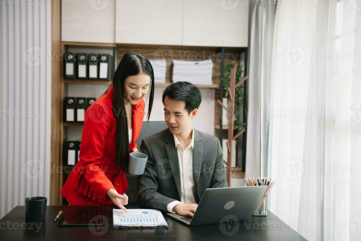 asiatisch Geschäft Kollege Geschäft die Geschenke und erklärt und mit Laptop und Tablette. Zusammenarbeit, finanziell Marketing Team, während Sitzung im modern Büro foto