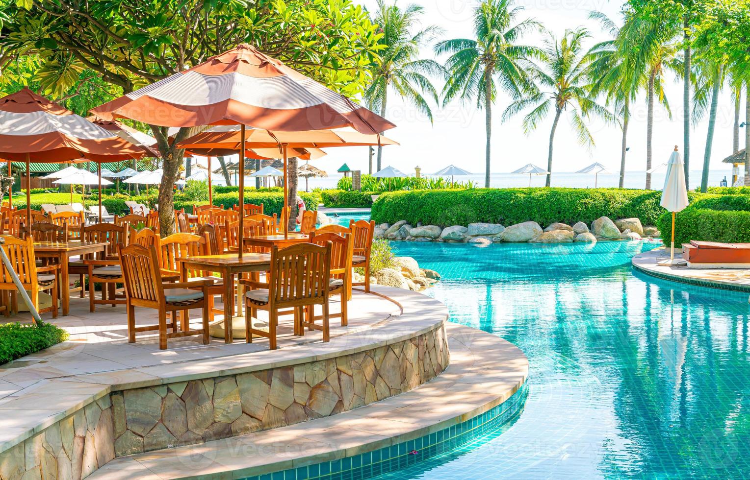 Sonnenschirm mit Stuhl und Tisch rund um den Pool foto