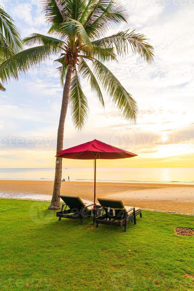 Regenschirm mit Stuhl mit Strandhintergrund und Sonnenaufgang am Morgen foto