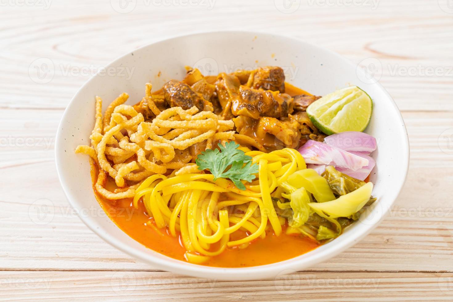 Nordthailändische Nudel-Curry-Suppe mit geschmortem Schweinefleisch foto