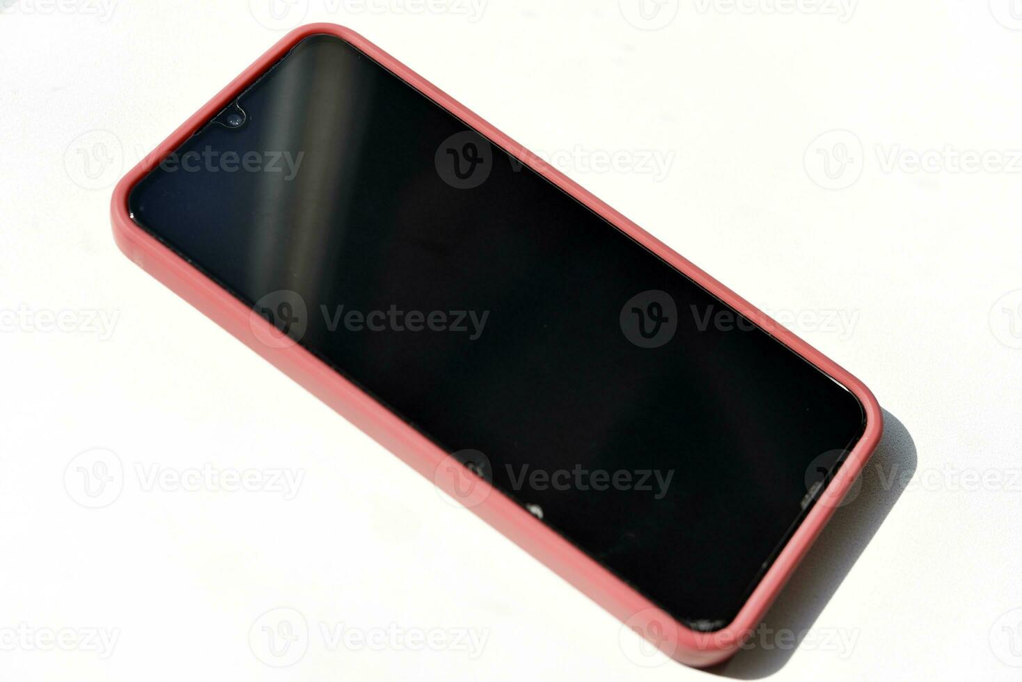 ein Smartphone im ein rot Fall und ein schwarz Bildschirm. rot Telefon auf ein Weiß Hintergrund. foto