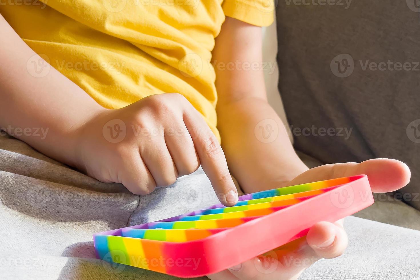 buntes Anti-Stress-Sinneszappel-Push-Pop-It-Spielzeug in Kinderhänden foto