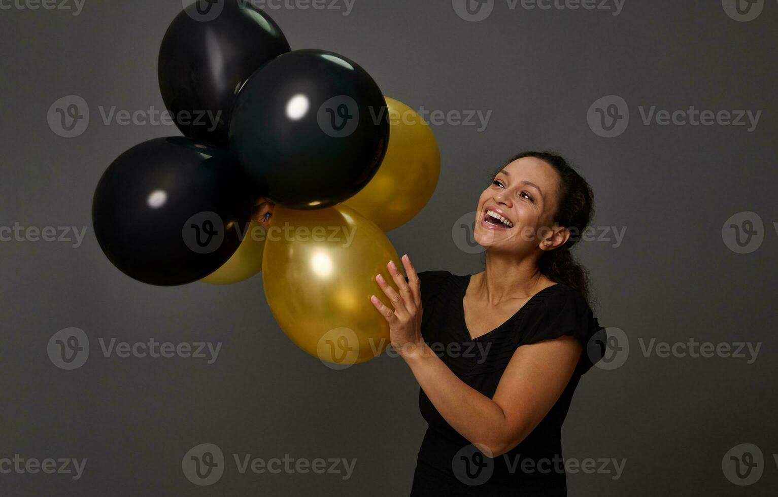 heiter lächelnd schön Frau halten Gold schwarz glänzend aufgeblasen Luft Luftballons gegen grau Mauer Hintergrund mit Kopieren Raum. golden Luftballons- Konzept von Gold Anerkennung Karte. schwarz Luftballons- schwarz Freitag foto