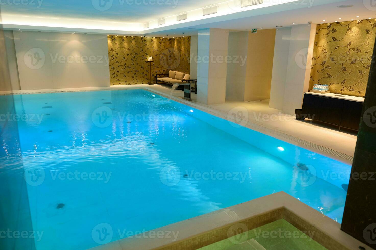 Aussicht von ein schön geräumig Innere mit Innen- Thermal- Schwimmen Schwimmbad mit Wasserfall im ein luxuriös Salon Bereich von ein Wellness Spa Resort foto