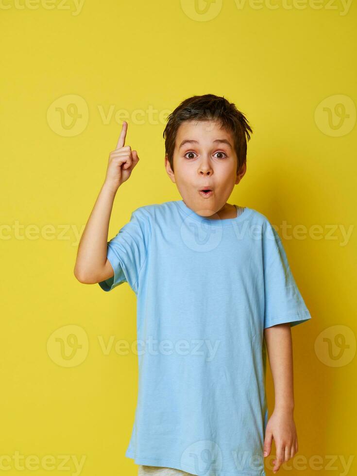 überrascht Junge, zeigen Index Finger oben auf ein Gelb Hintergrund mit Kopieren Raum. Gesicht Emotionen, Überraschung. Konzepte foto
