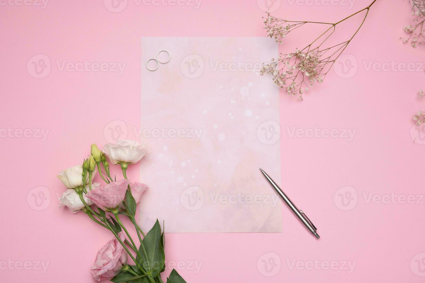 zwei Luxus Ringe, Silber Stift und Hochzeit Einladung Brief zum frisch verheiratet Gäste auf Rosa Hintergrund mit schön Blumen foto