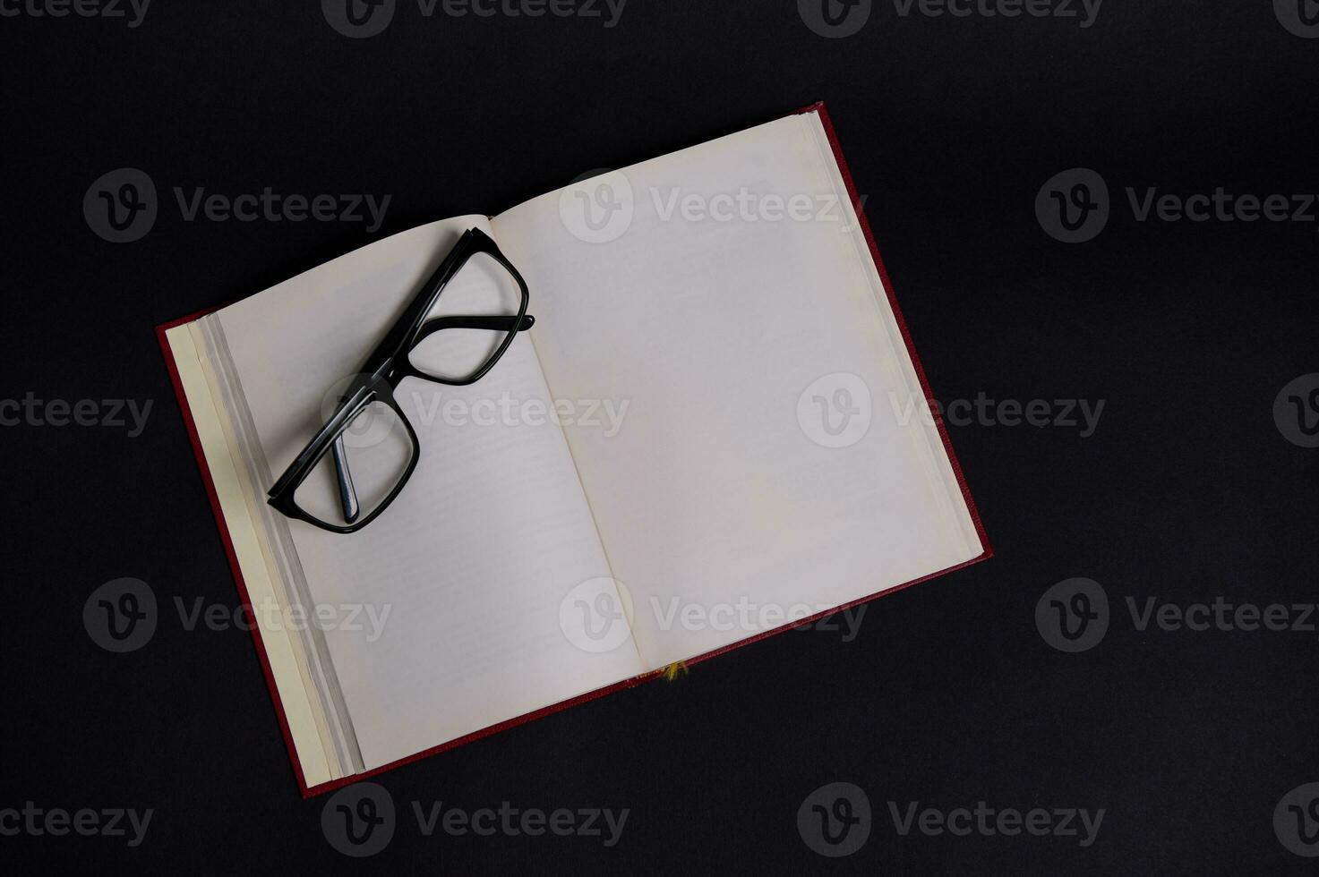 eben legen von Brille auf ein geöffnet Buch im schwer rot Abdeckung, isoliert Über schwarz Hintergrund mit Raum zum Text. Lehrer Tag Konzept, Wissen, Literatur ,Lektüre, Gelehrsamkeit foto