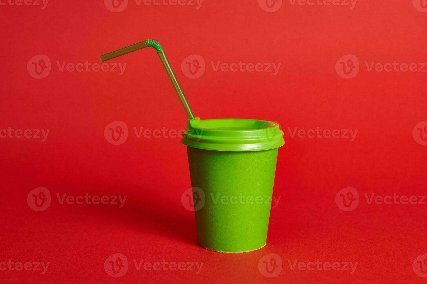 Vorderseite Aussicht von ein Grün recycelbar Karton Tasse mit ein Stroh auf ein rot Hintergrund. Kopieren Raum. Schuss mit Sanft Schatten. Farbe Kontrast foto