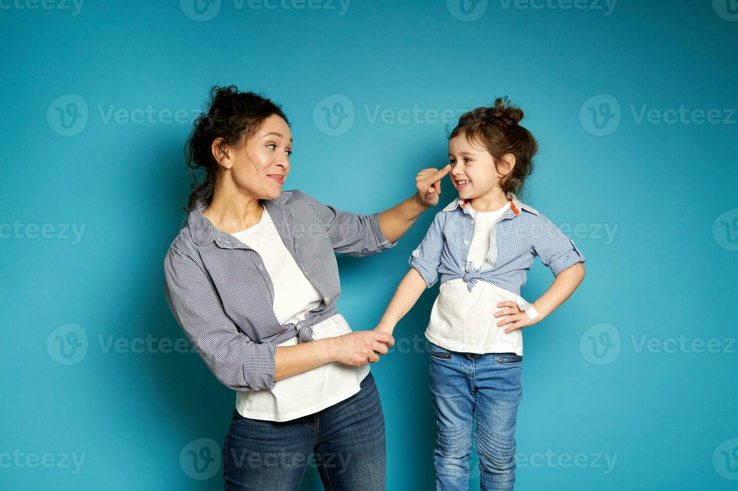 lächelnd Frau berühren ihr bezaubernd Tochter Nase auf Blau Hintergrund mit Kopieren Raum foto