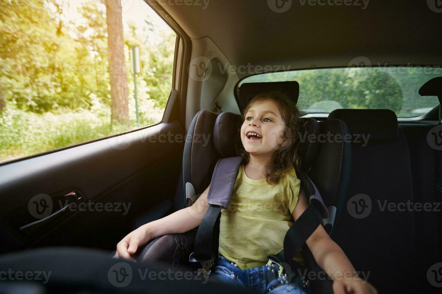 glücklich Mädchen im ein Kind Auto Sitz tragen ein Sicherheitsgurt während Reisen durch Auto foto