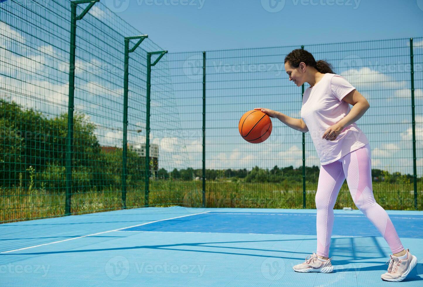 jung Basketball Spieler Füllung ein Basketball Ball auf das Gericht draussen foto