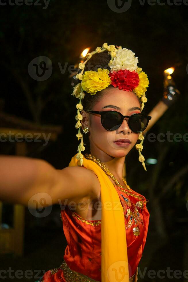 ein javanisch Tänzer Tänze sehr geschickt während tragen Sonnenbrille auf ihr Augen und sehr schön Gesichts- bilden foto