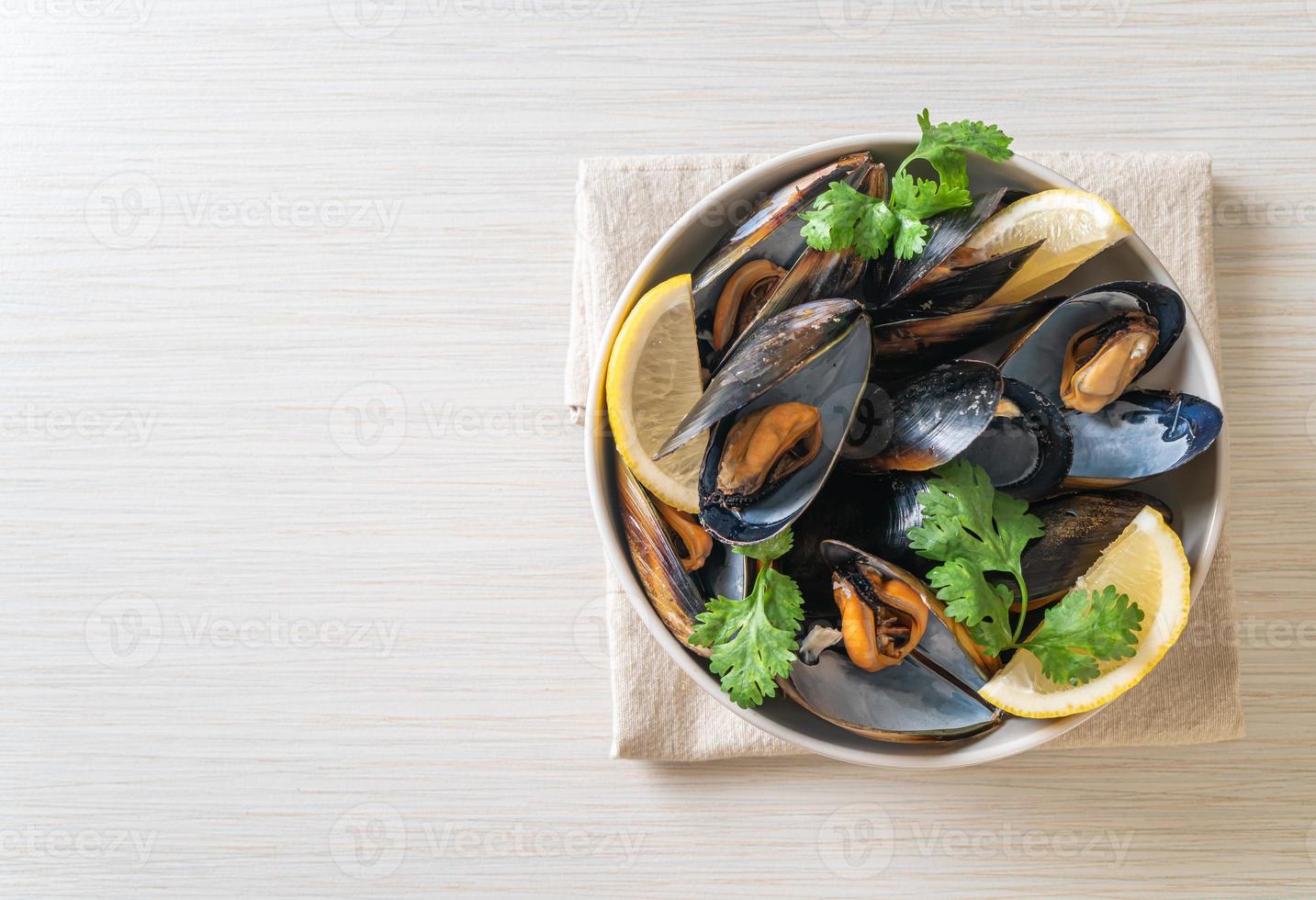 Muscheln mit Kräutern in einer Schüssel mit Zitrone foto