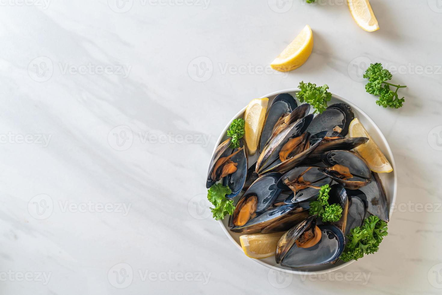 Muscheln mit Kräutern in einer Schüssel mit Zitrone foto