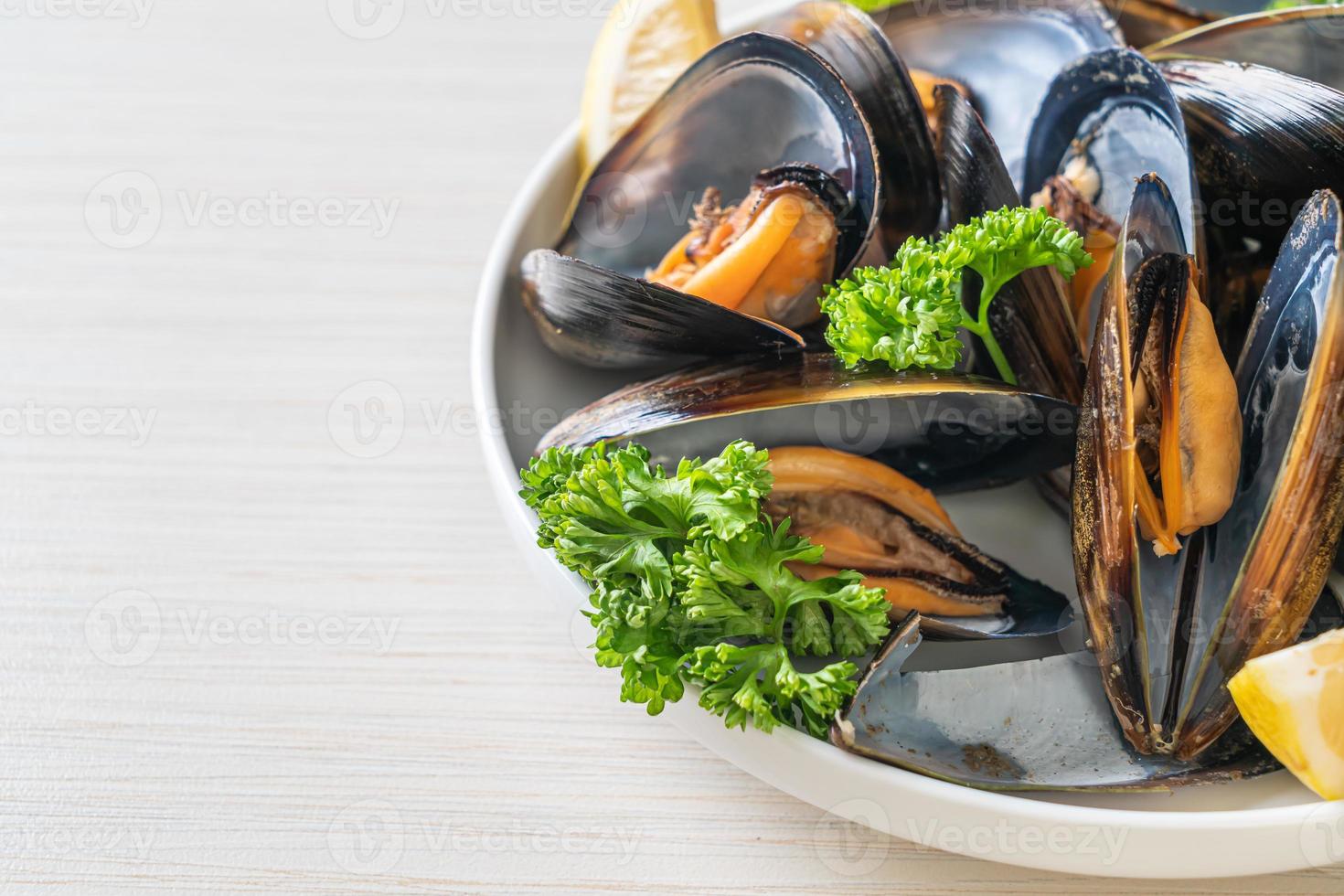 Muscheln mit Kräutern in einer Schüssel mit Zitrone foto