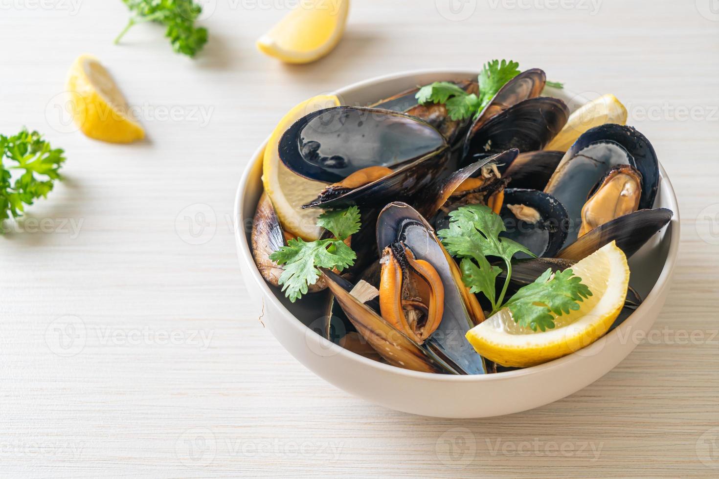 Muscheln mit Kräutern in einer Schüssel mit Zitrone foto