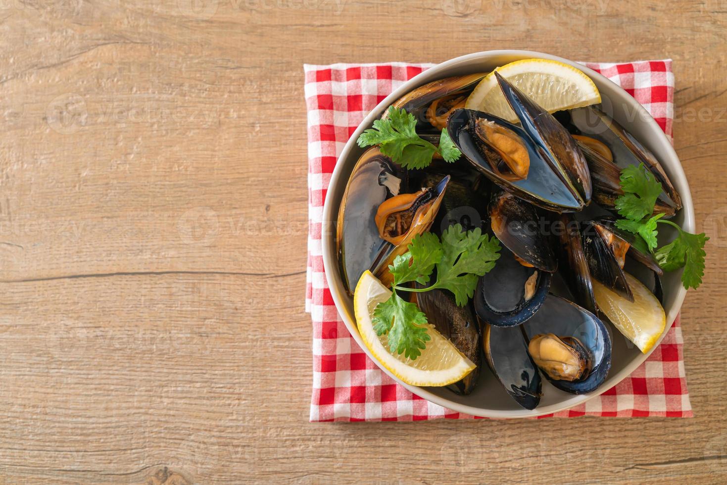 Muscheln mit Kräutern in einer Schüssel mit Zitrone foto