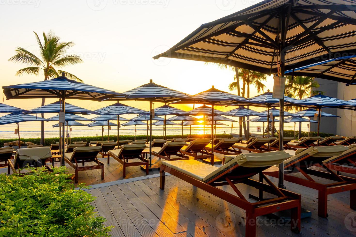 Sonnenschirm und Stuhlsofa rund um den Außenpool im Hotelresort für den Reiseurlaub? foto