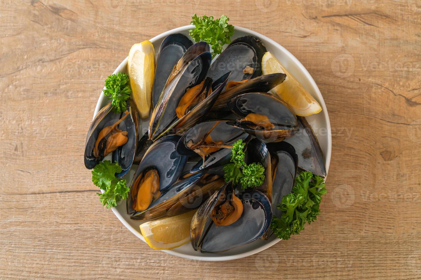 Muscheln mit Kräutern in einer Schüssel mit Zitrone foto