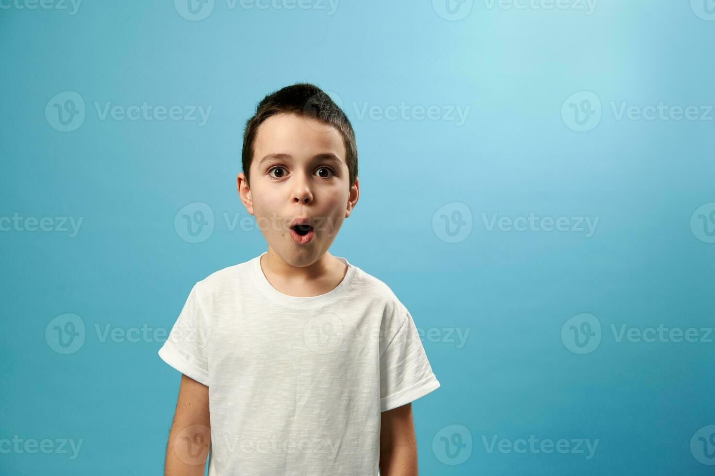 schockiert Junge posieren mit geöffnet Mund ausdrücken Überraschung auf Blau Hintergrund foto