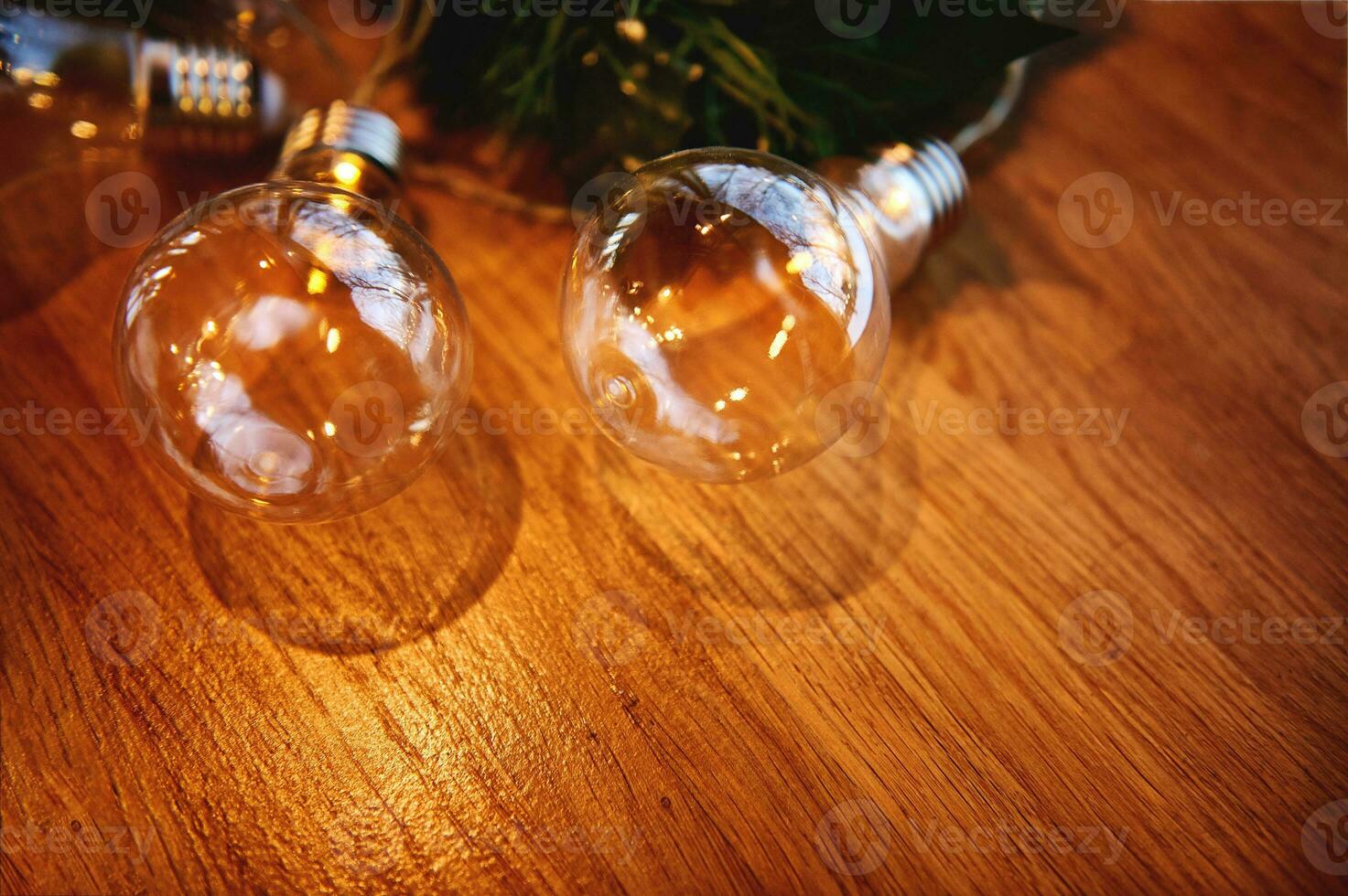 eben legen Komposition mit Ornament von transparent Lampen auf ein Kiefer Ast Lügen auf ein hölzern Tafel. hölzern Hintergrund foto