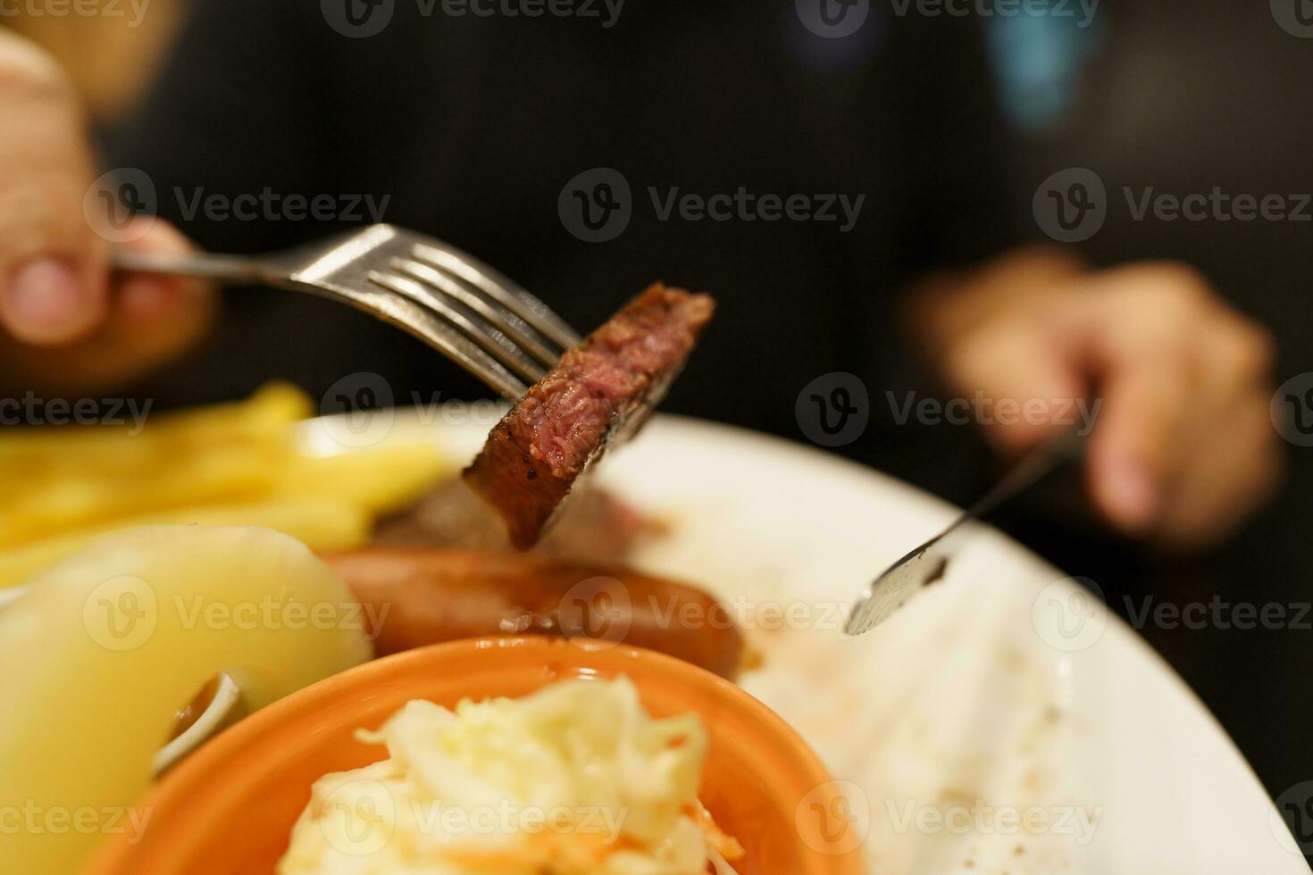 Mann Essen gegrillt Fleisch Anteil von Platte. Hand halten Messer und Gabel Schneiden gegrillt Rindfleisch Steak foto