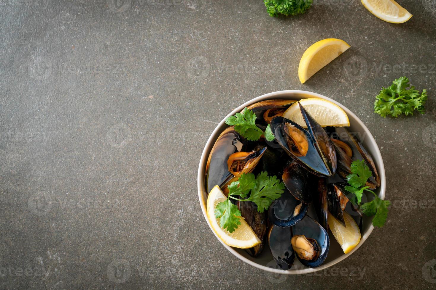 Muscheln mit Kräutern in einer Schüssel mit Zitrone foto