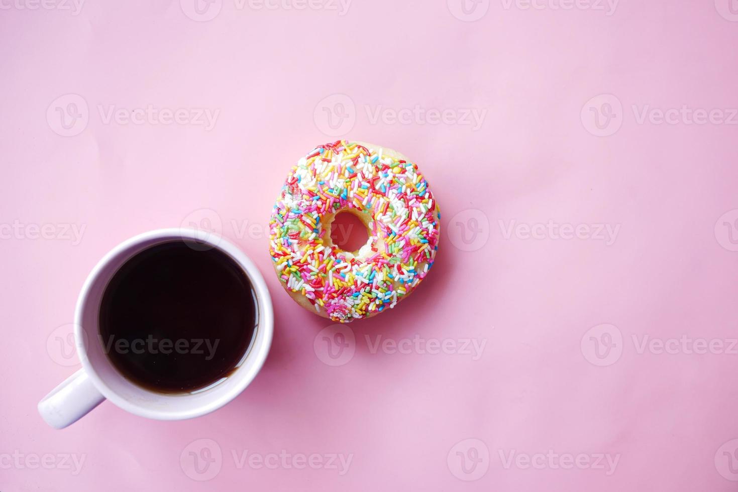 Draufsicht auf bunte leckere Donuts und Kaffeetasse auf Rosa on foto