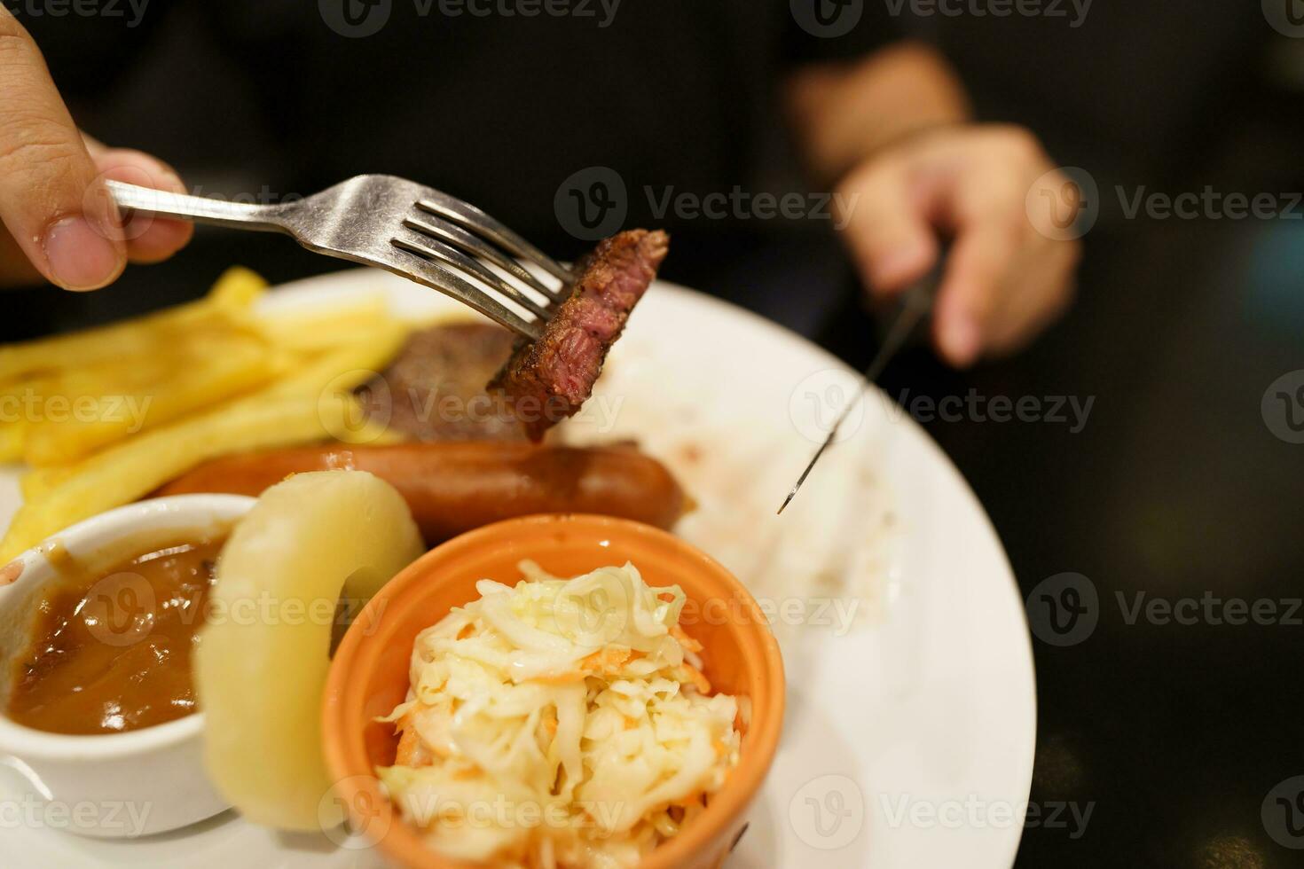 Mann Essen gegrillt Fleisch Anteil von Platte. Hand halten Messer und Gabel Schneiden gegrillt Rindfleisch Steak foto