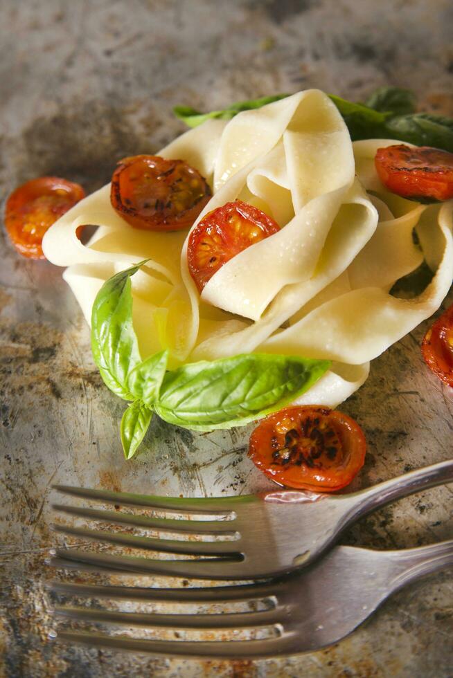 Nest aus Nudeln mit Basilikum und Tomate foto