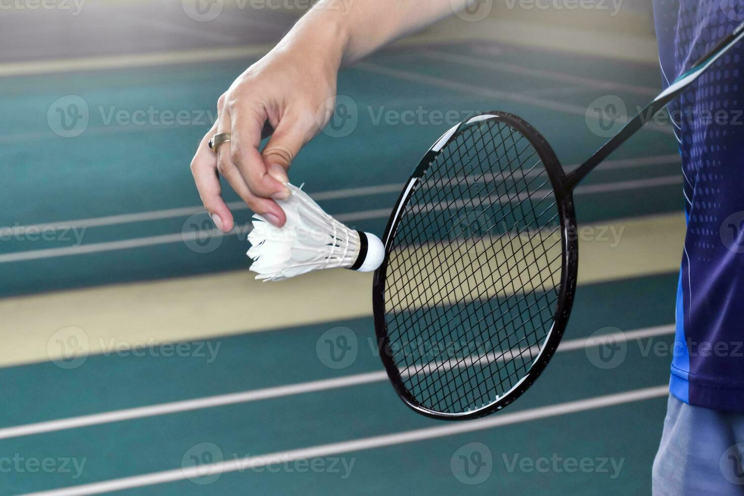 Badminton Spieler hält Schläger und Weiß Sahne Federball im Vorderseite von das Netz Vor Portion es zu Ein weiterer Seite von das Gericht foto