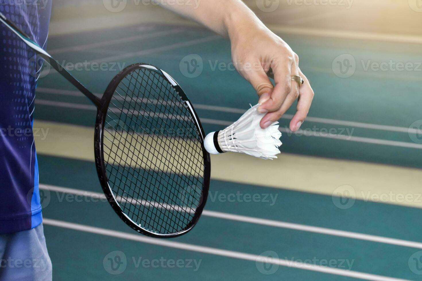 Badminton Spieler hält Schläger und Weiß Sahne Federball im Vorderseite von das Netz Vor Portion es zu Ein weiterer Seite von das Gericht foto