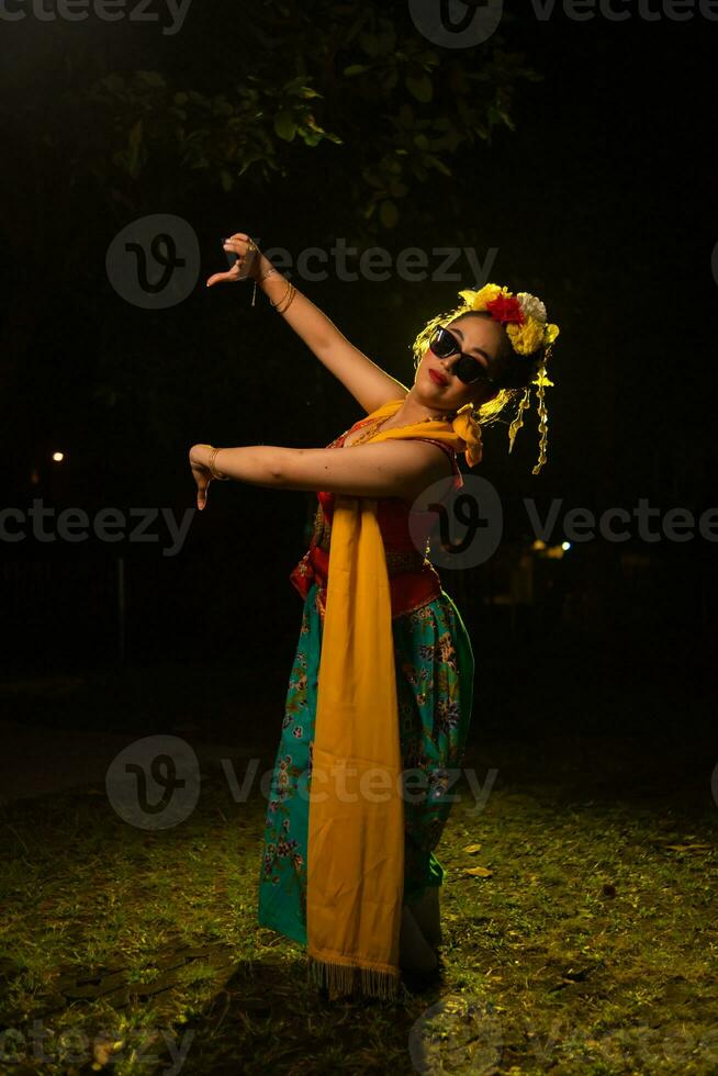 ein traditionell indonesisch Tänzer Tanzen mit das Körper Verdrehen auf Bühne foto