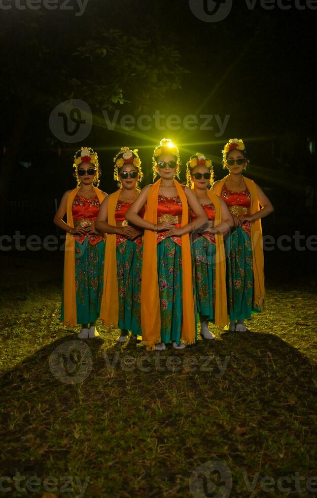 ein Gruppe von indonesisch traditionell Tänzer tanzen mit ihr freunde im Vorderseite von das Bühne Beleuchtung foto