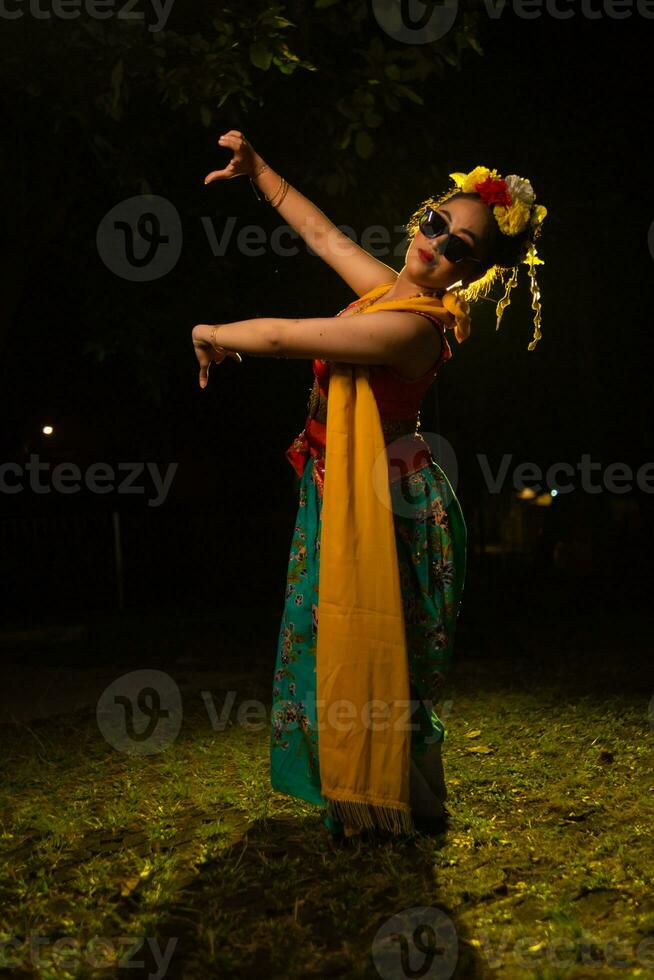 ein traditionell indonesisch Tänzer Tanzen mit das Körper Verdrehen auf Bühne foto