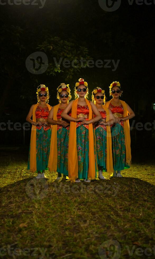 ein Gruppe von indonesisch traditionell Tänzer tanzen mit ihr freunde im Vorderseite von das Bühne Beleuchtung foto