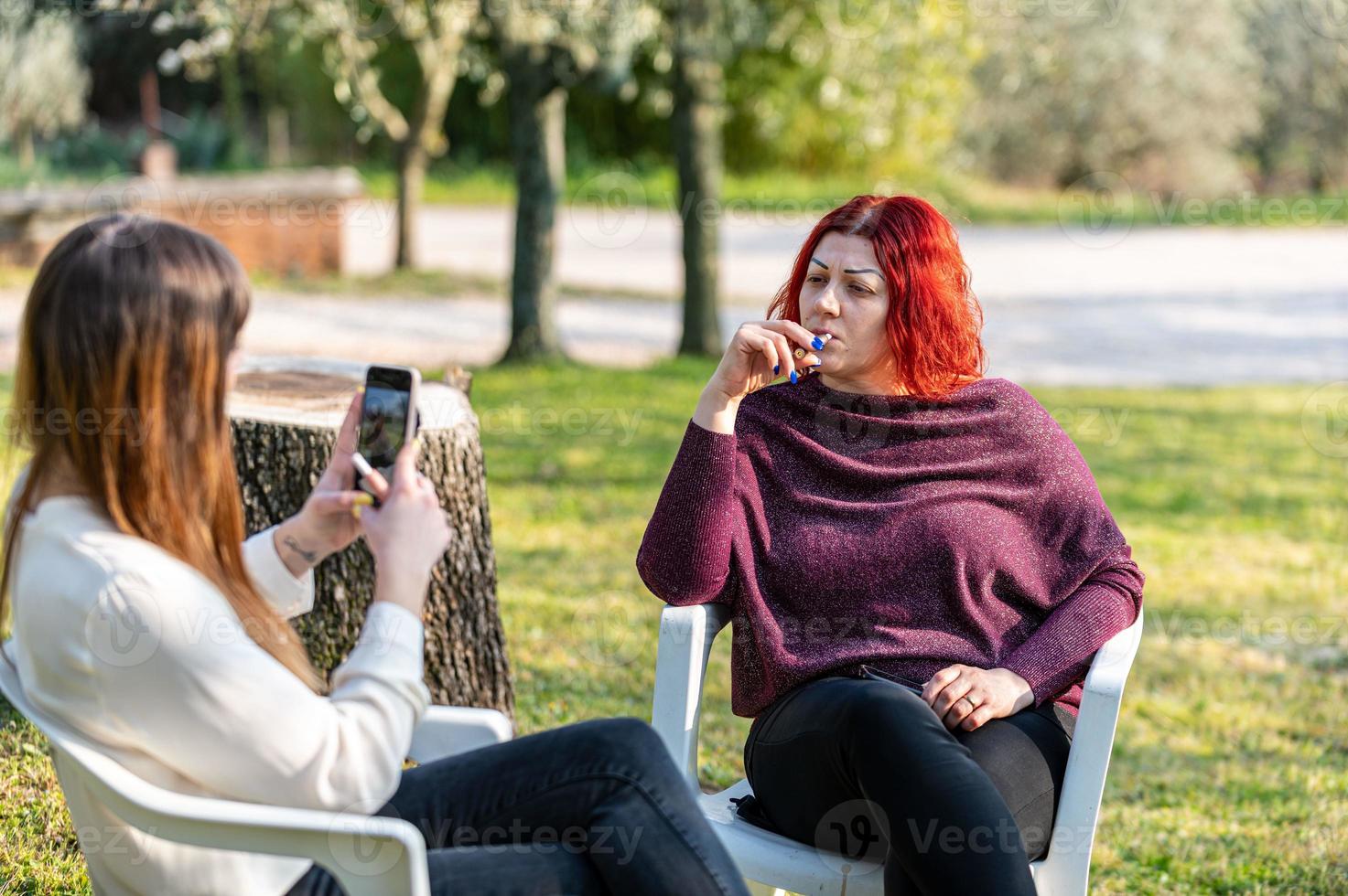 Freundinnen mit Smartphone und Zigarette rauchen foto