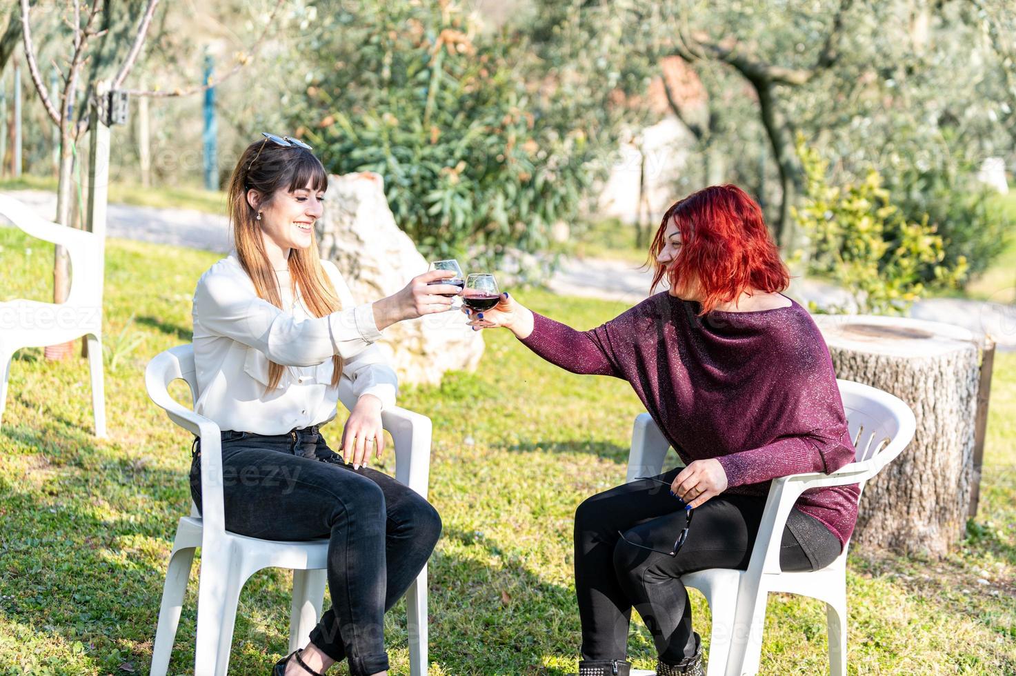 Mädchen stoßen mit einem Glas Rotwein an foto