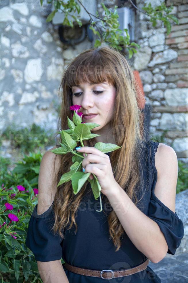 ein langhaariges Mädchen, das Blumen schnüffelt foto