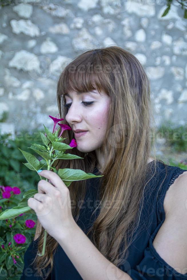 ein langhaariges Mädchen, das Blumen schnüffelt foto