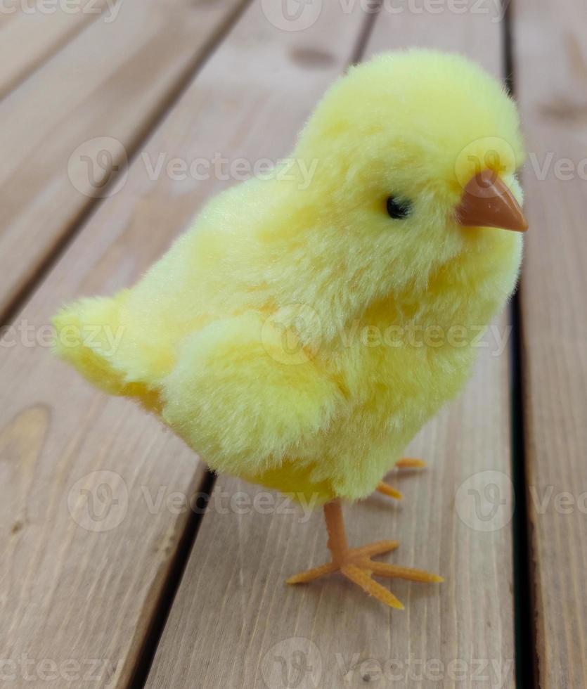 Ostern gelbes Spielzeughuhn steht auf den Brettern. foto