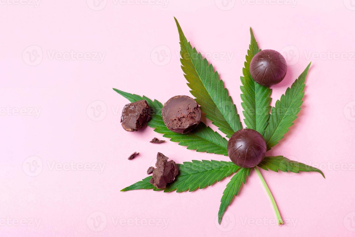 Cannabis-Schokoladenbonbons auf grünem Blattrosa-Hintergrund foto