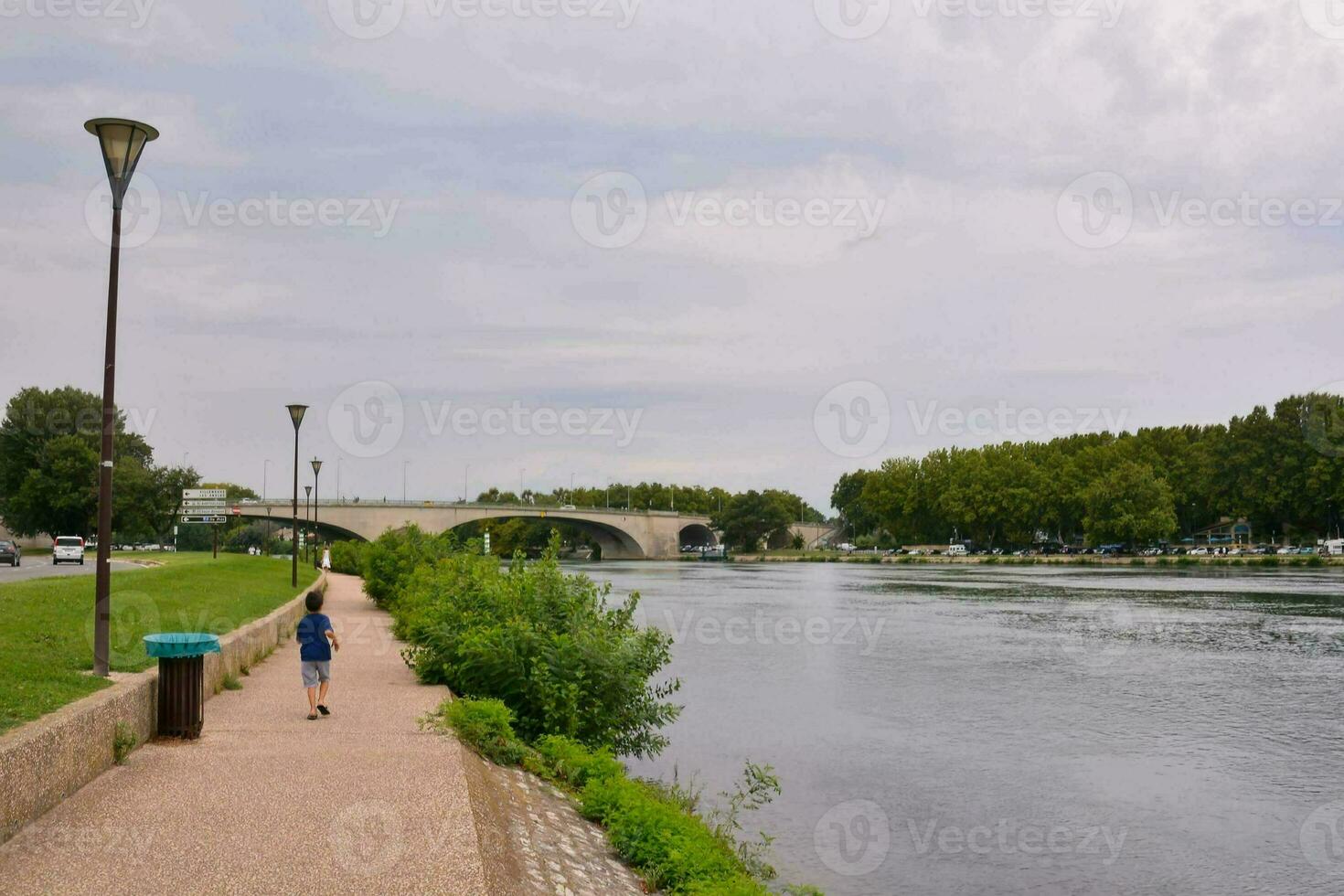 ein Mann Gehen entlang das Fluss Bank in der Nähe von ein Brücke foto