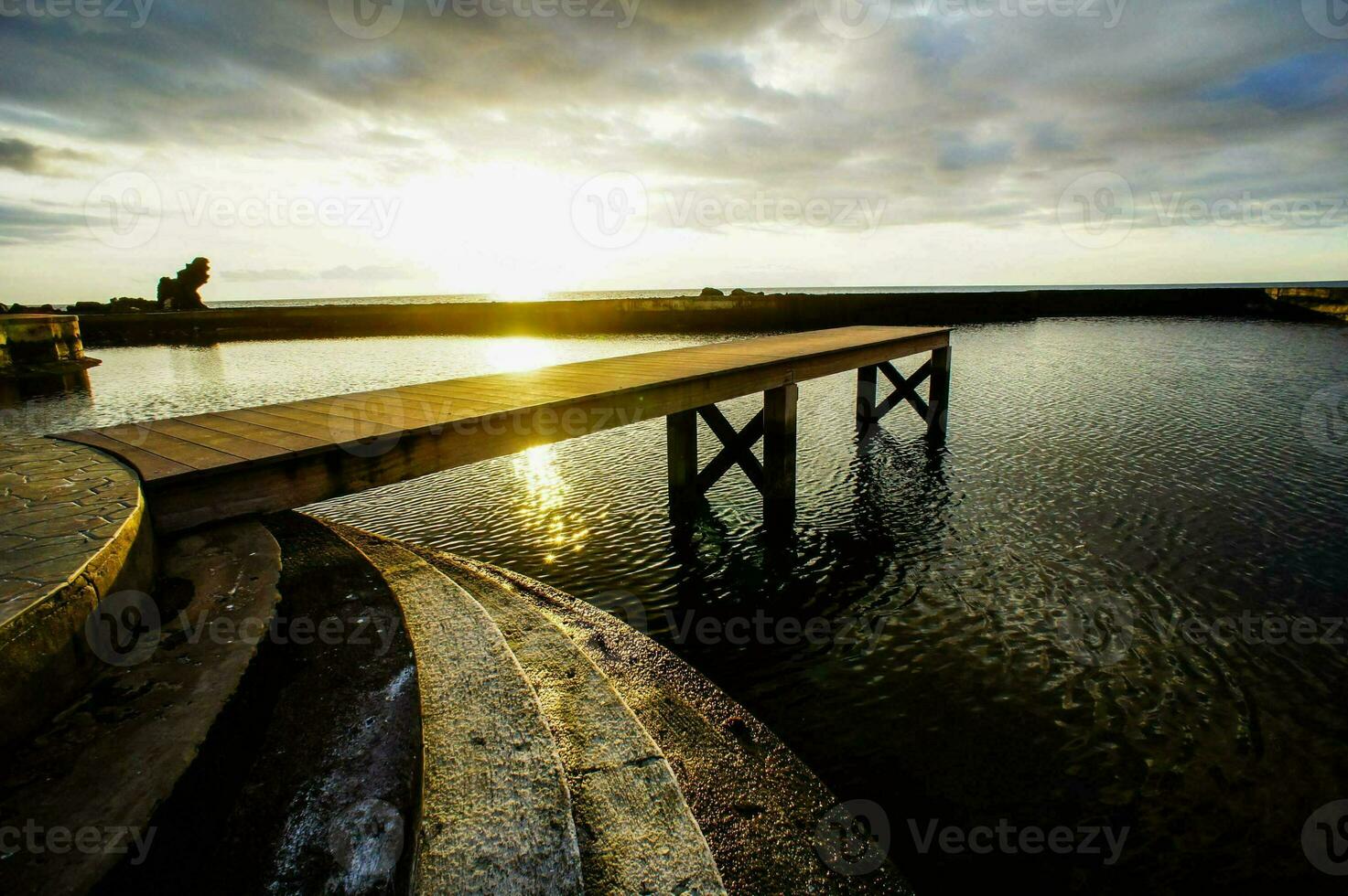 ein Seebrücke beim Sonnenuntergang mit das Sonne leuchtenden durch das Wolken foto